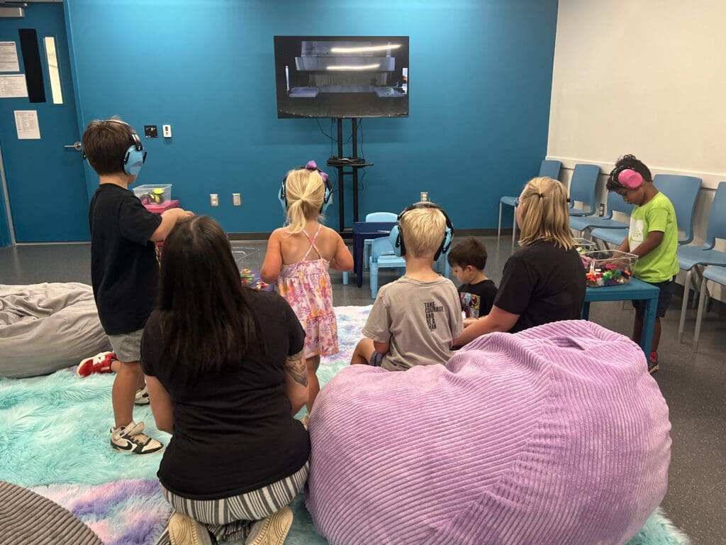 Children wearing noise cancelling headphones and enjoying soft bean bag seating in a sensory friendly room