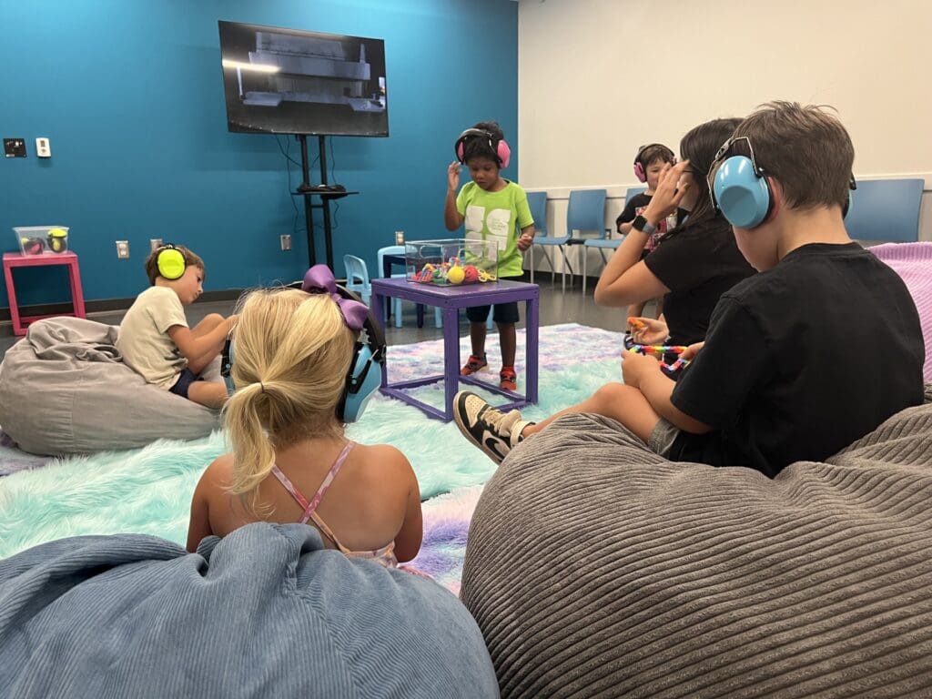 Children wearing noise cancelling headphones and enjoying soft bean bag seating in a sensory friendly room
